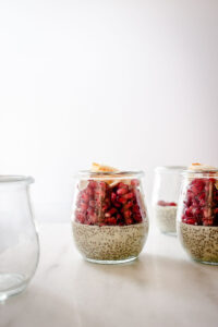 Small glass jars, two are filled with chia pudding and pomegranate
