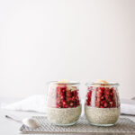 Two jars filled with chia pudding and a spoon setting on a wire rack