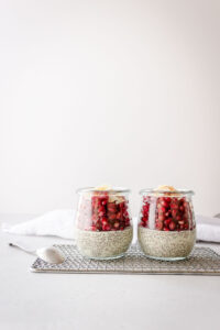 Two jars filled with chia pudding and a spoon setting on a wire rack