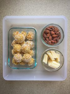 Plastic container with energy balls, almonds and cheese