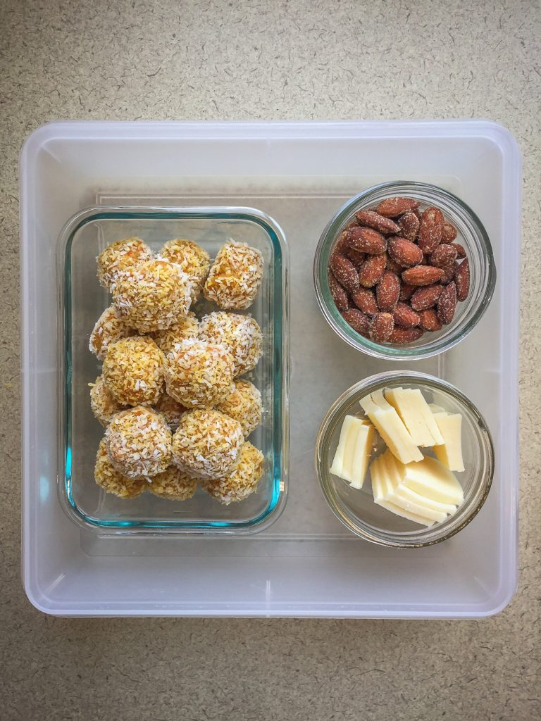 Plastic container with energy balls, almonds and cheese