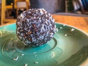 Turquoise plate with a large chocolate energy ball on it that has been rolled in coconut