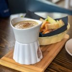 Basket of apple slices and bread next to a small pot of cheese fondue