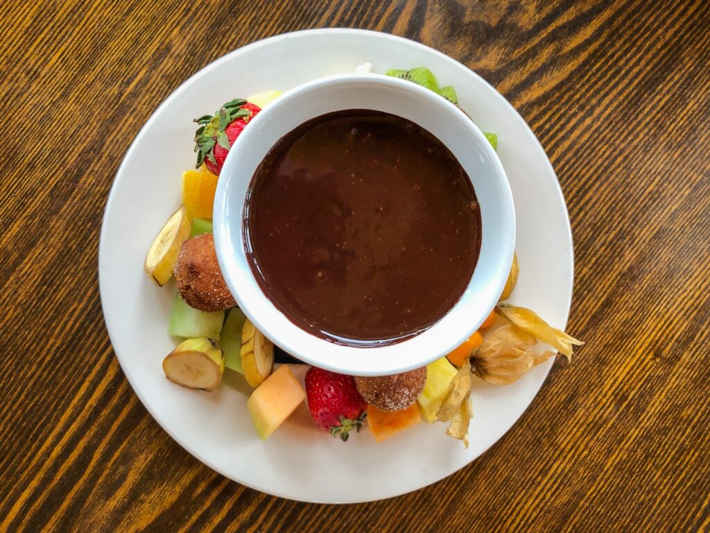 top down view of a plate of fruit with a bowl of chocolate fondue