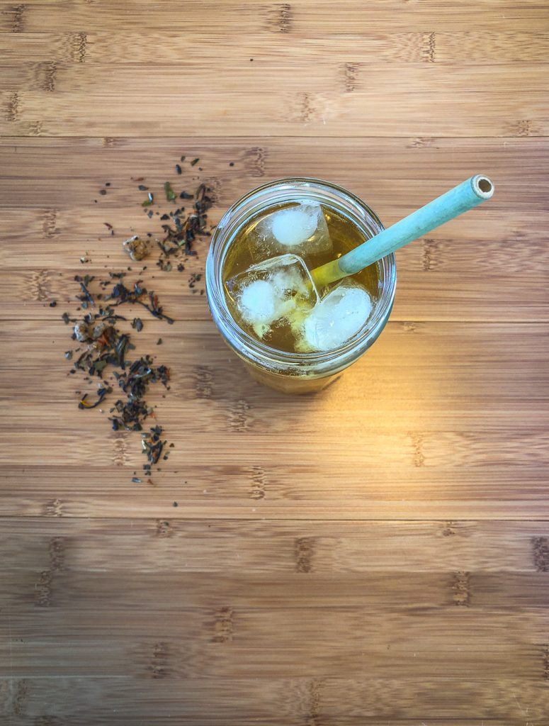 Top down photo of glass with iced tea with some loose leaf tea sprinkled next to it