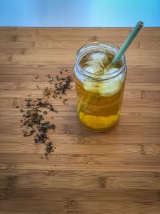 Glass of iced tea with a straw, with some loose leaf tea sprinkled next to it