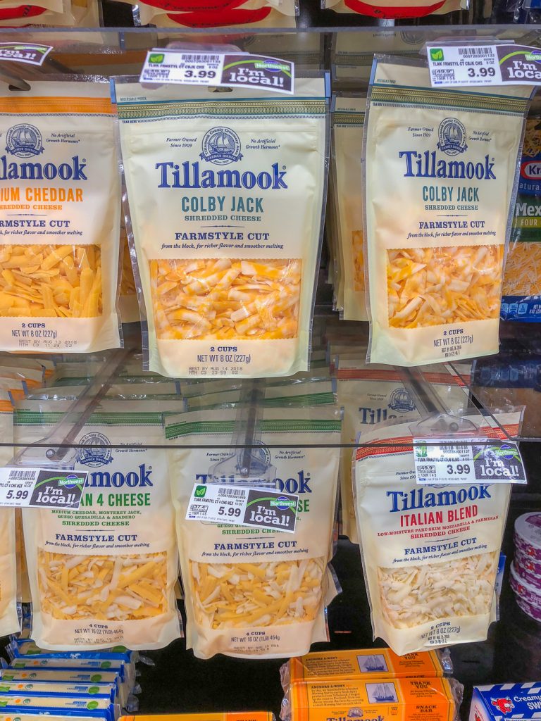 Bags of pre-shredded cheese hanging in a grocery store display case