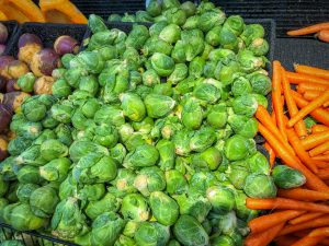 Piles of Brussels sprouts and carrots in a grocery store produce section