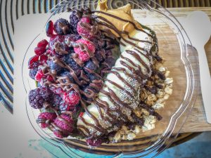 Overhead shot of a smoothie bowl covered with fruit, granola and chocolate drizzle