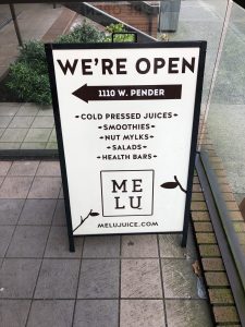 Sandwich board sign on patio advertising Melu Juice