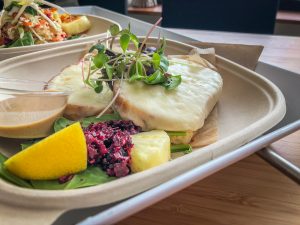 Two pieces of bread with melted cheese topped with micro greens