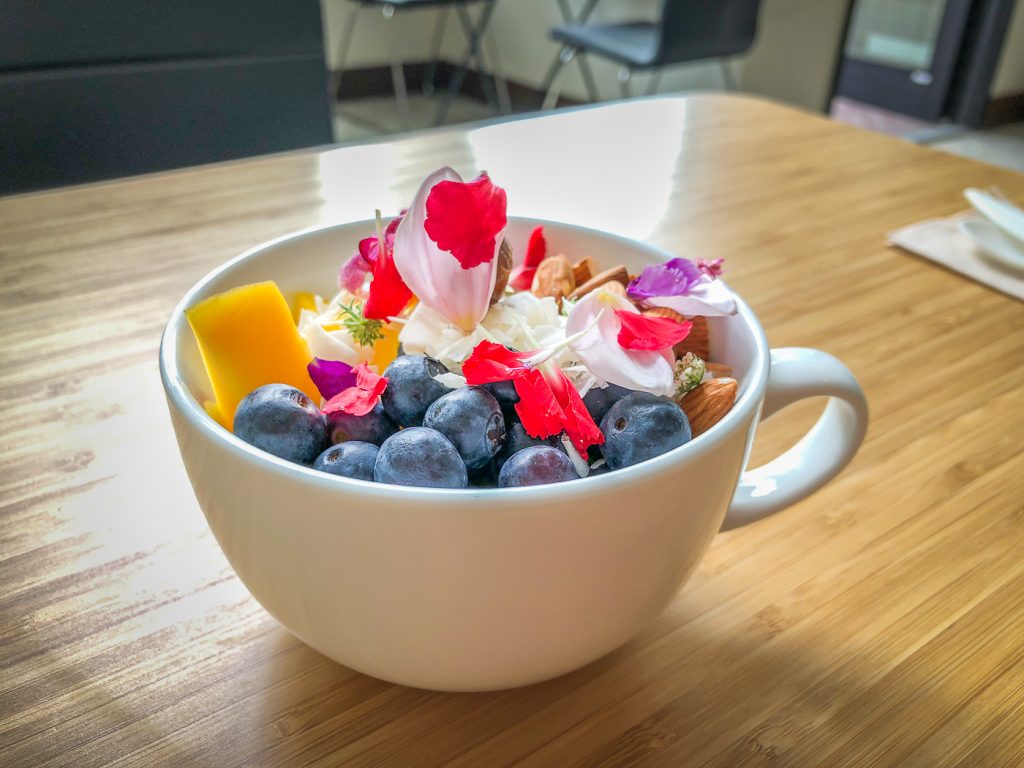 Large tea cup filled with edible flowers and fruit on a bamboo table