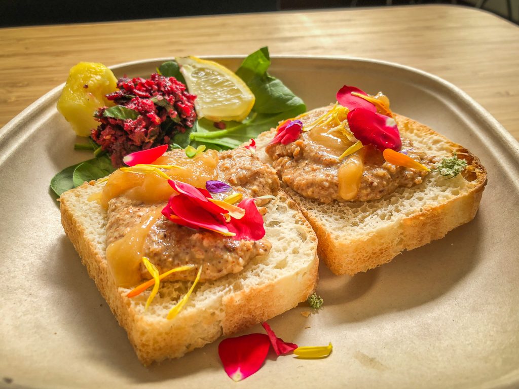 Two pieces of toast with almond butter and honey and edible flowers