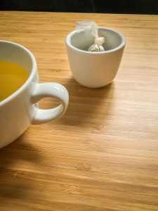 Tea cup and a small cup to hold the teabag on a bamboo table