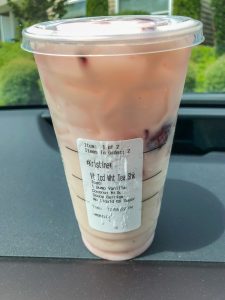 Starbucks cup with order sticker on car dashboard white tea