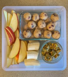 Plastic container filled with fruit, nut bites and energy balls