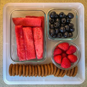 Plastic container filled with fruit and cookies