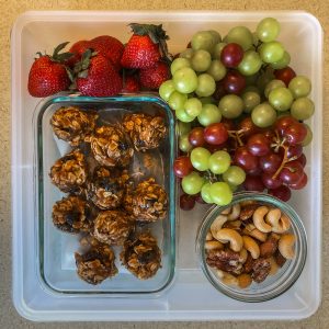 Plastic container filled with fruit, cookies and nuts