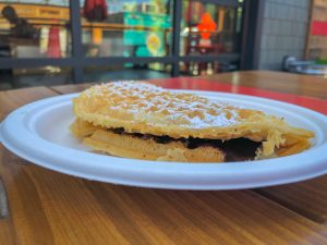 Folded waffle filled with peanut butter and chocolate on a paper plate