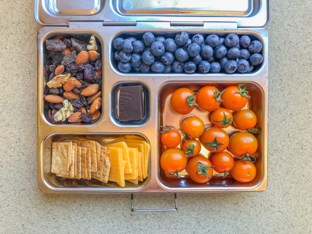 Metal lunchbox filled with berries and tomatoes