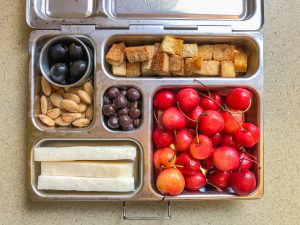 Metal lunch box filled with fruit and tofu