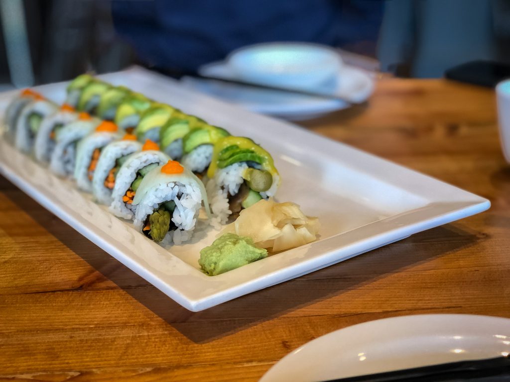 Oblong plate with two rows of sushi, garnished with wasabi and ginger