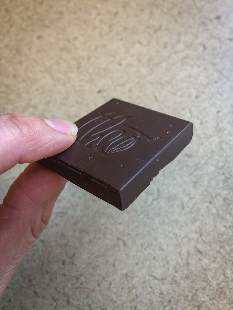 Fingers holding a piece of dark chocolate