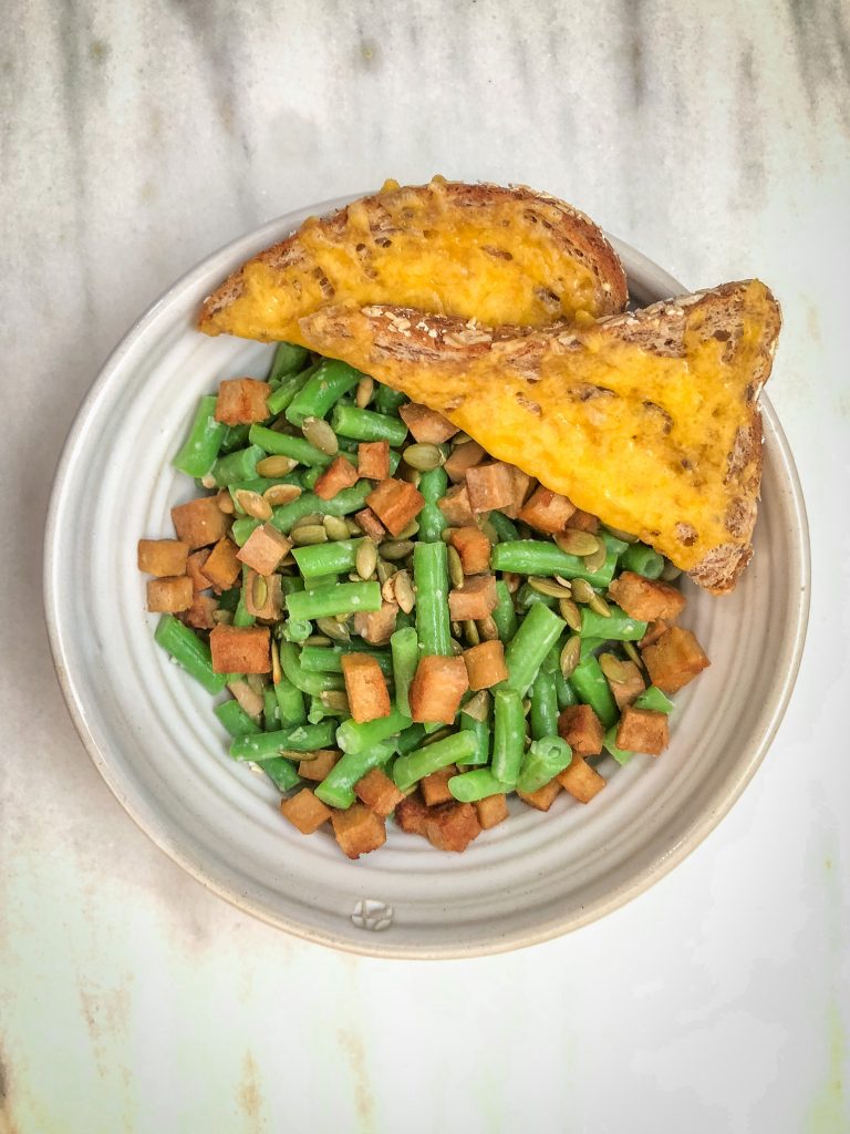 Bowl of green bean and tofu salad with a side of cheesy toast