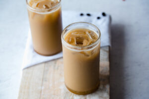 Looking down at two glasses of iced coffee on a wooden cutting board