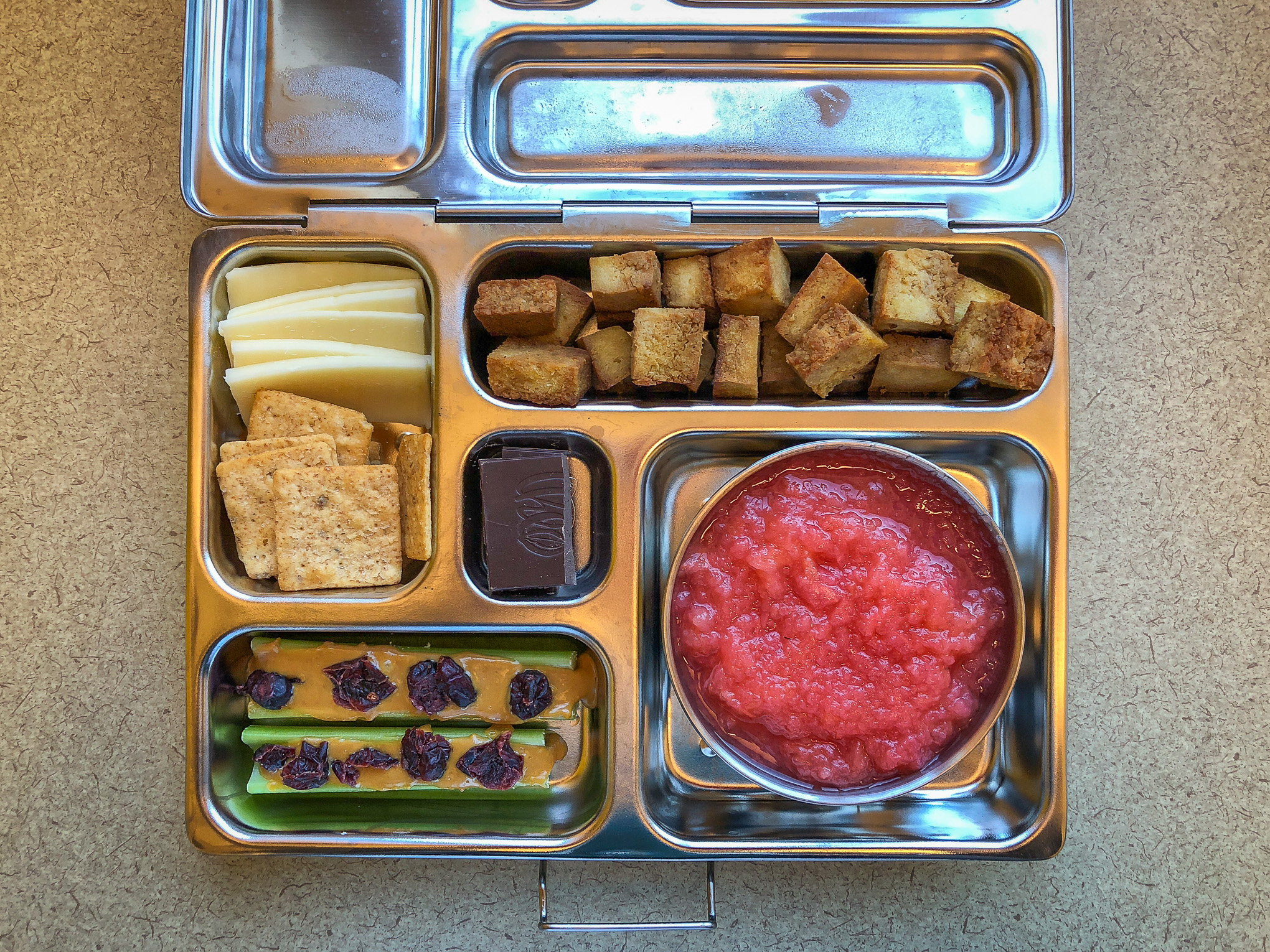 Bento box filled with tofu, applesauce and cheese