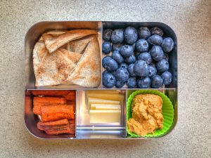 Bento box filled with pita chips and fruit
