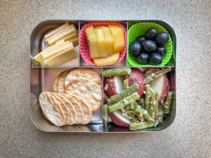 Bento box filled with cheese, fruit and vegetables