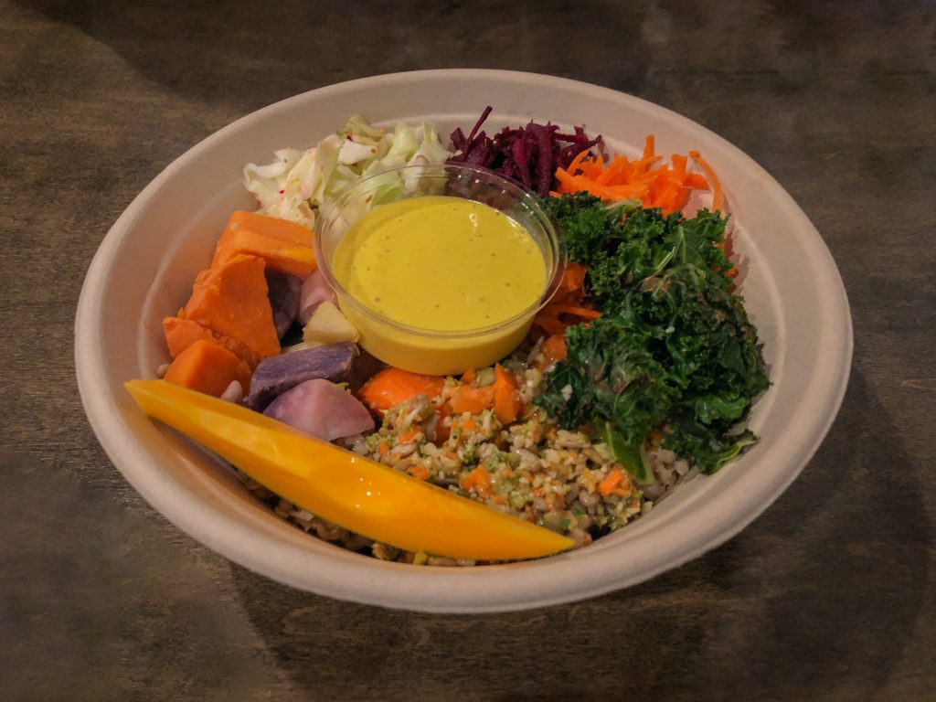 Bowl of colorful veggies and a little cup of sauce in the middle