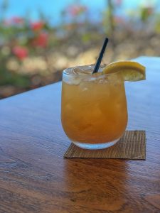 Glass with ice and peach flavored drink with lemon wedge