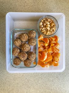 Tupperware filled with cashews, orange segments, and gingerbread bites