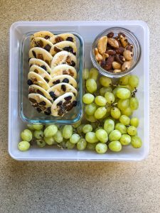 Tupperware filled with white chocolate, nuts and green grapes