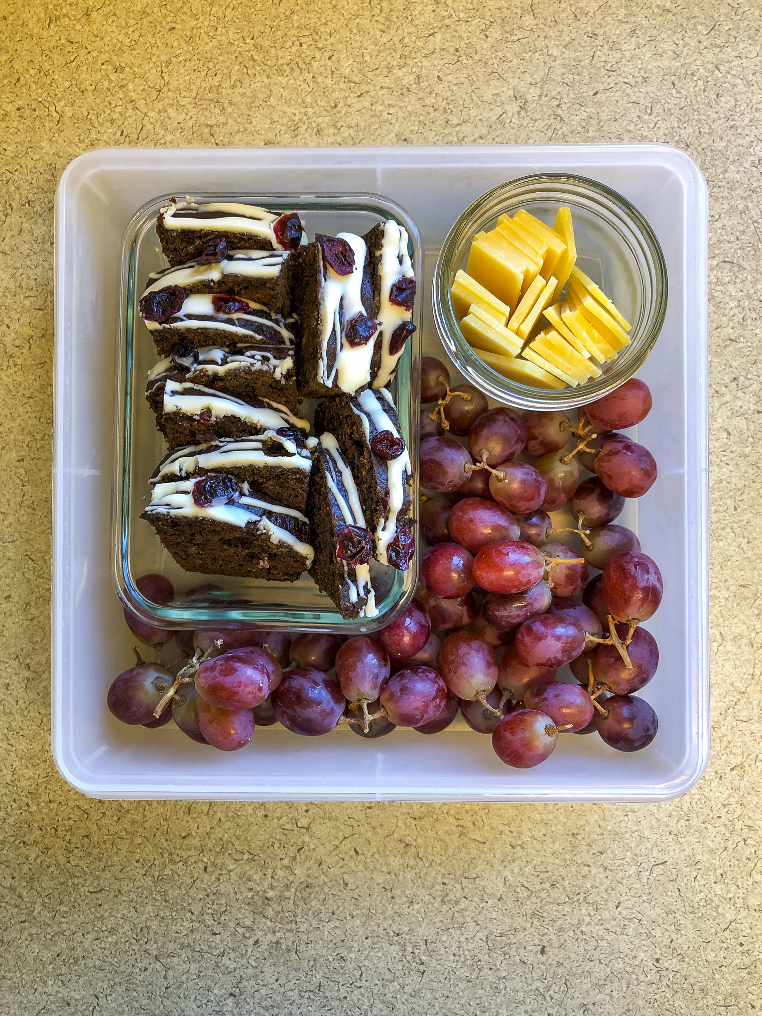 Tupperware filled with gingerbread, cheese and grapes