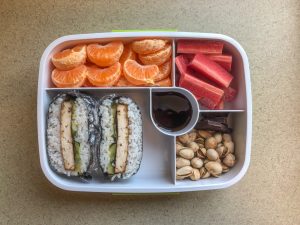 Bento box filled with sushi sandwiches and fruit