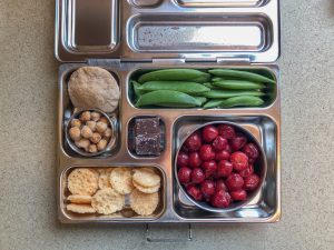 Bento box filled with snap peas, cherries, and pita