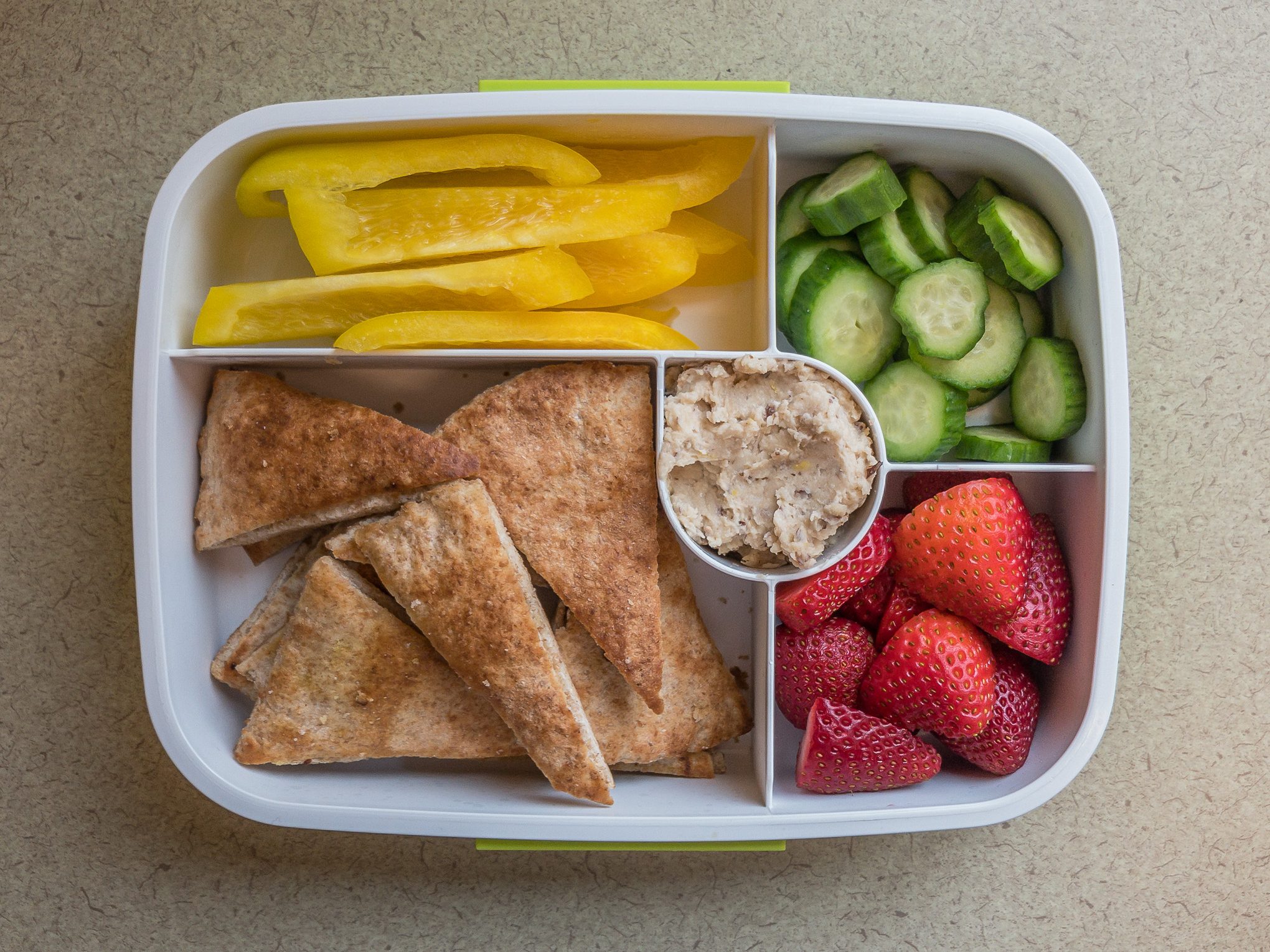 Bento box filled with pita chips and bean dip