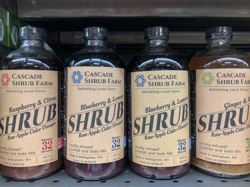 Bottles of shrub syrup lined up on grocery shelf