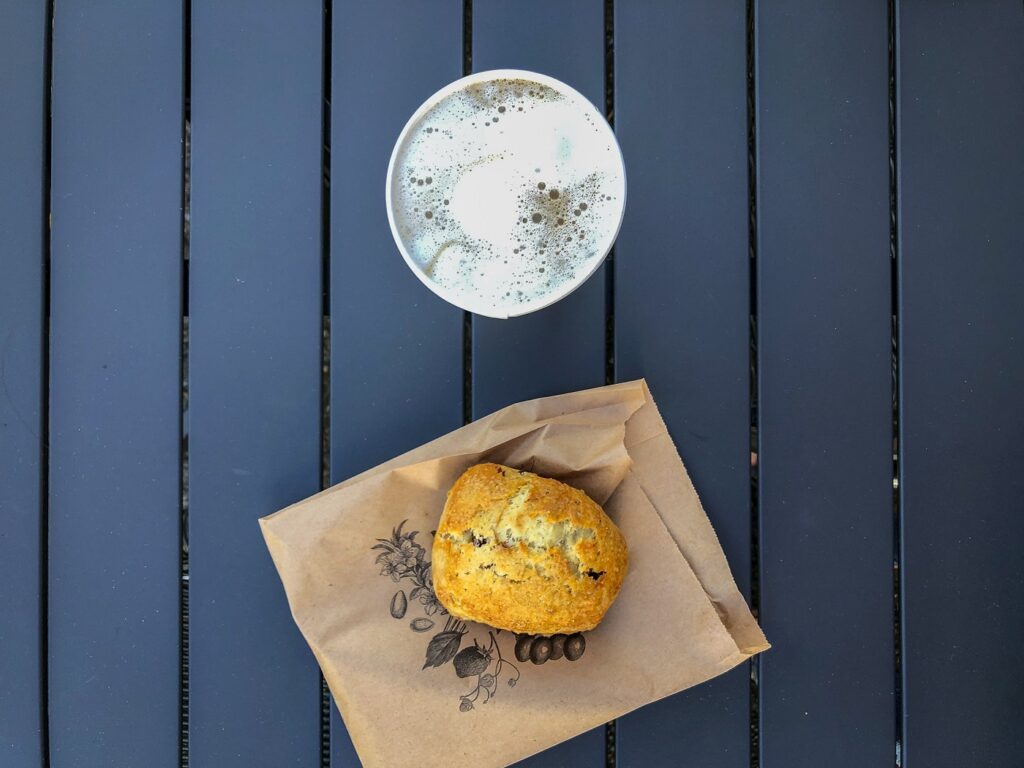 Top down view of roll and coffee on a picnic table