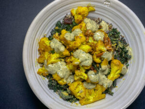 Top down picture of a bowl of greens and cauliflower