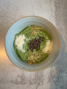 Bowl full of green smoothie and toppings