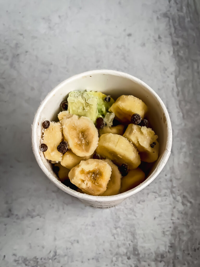 Paper smoothie cup full of frozen fruit and veggies