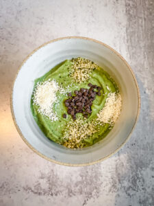 Bowl full of green smoothie and toppings