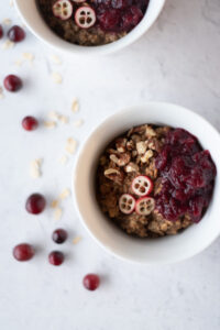 Small bowl of oats and quinoa topped with cranberries and pecans