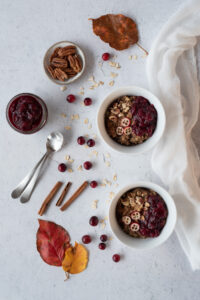 Top down picture of bowls of hot cereal, cranberries, and pecans