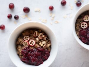 Top down picture of a white bowl filled with nuts, cranberries and hot cereal