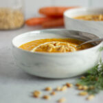 Side view of white marble bowl filled with carrot soup